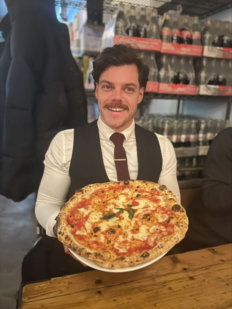 Daniel holding a pizza