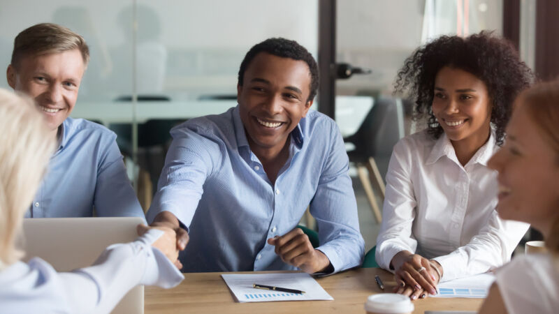 Smiling african manager handshaking greeting caucasian client at group negotiations AdobeStock 261524034 1